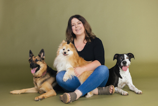 A foster pet parent seated with her three rescue dogs